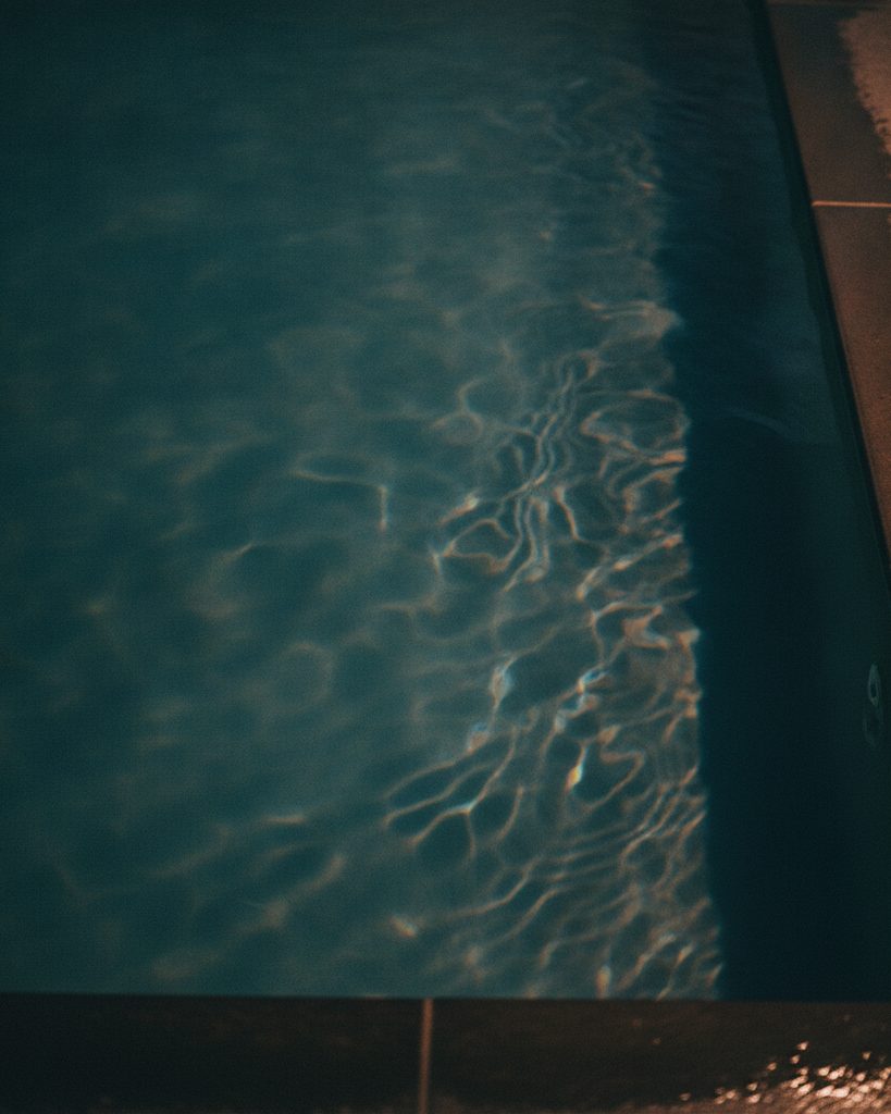 Still deep teal cold plunge water with rippling caustic light