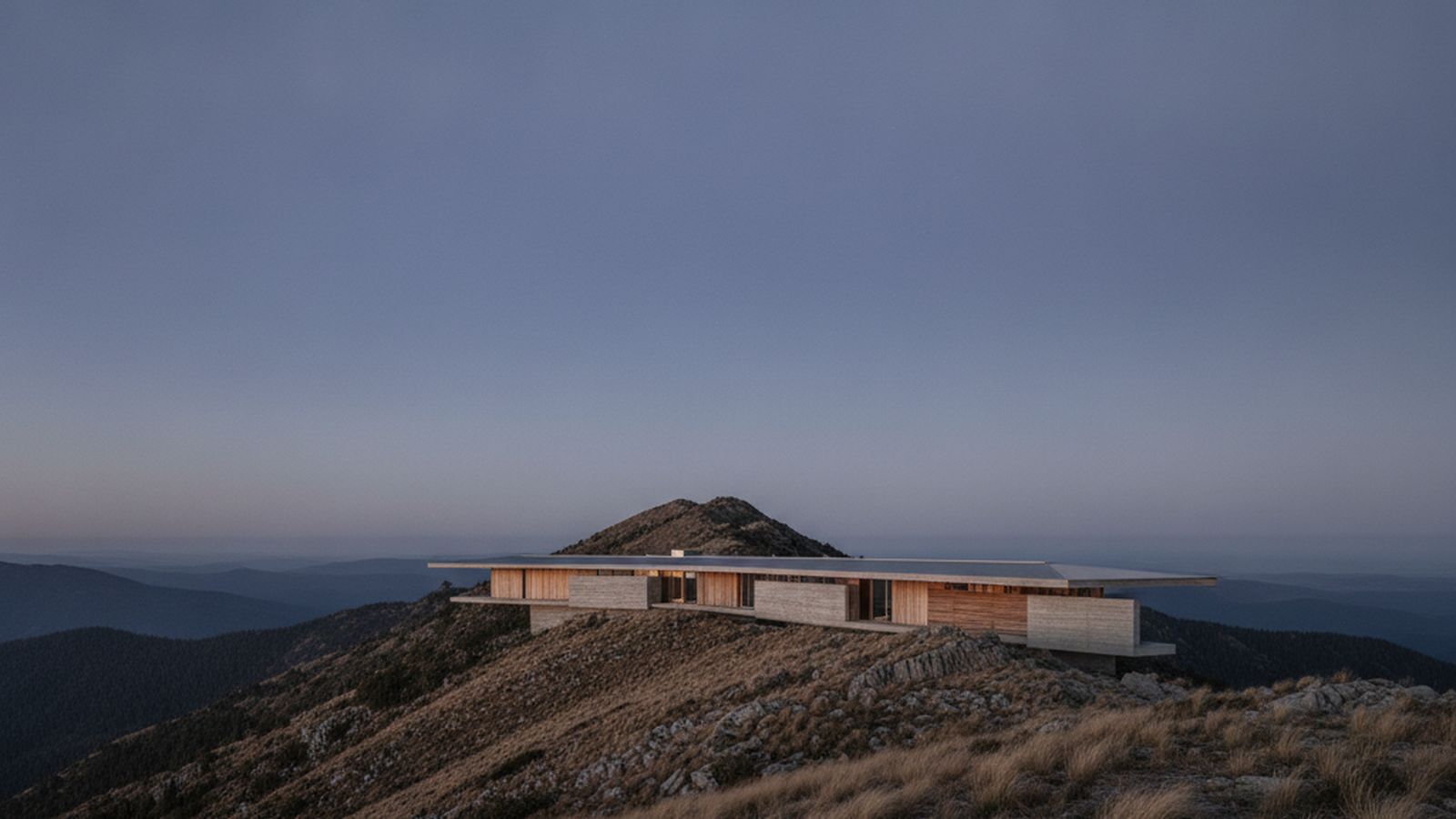 Ridgeline House — the long low massing seen along the ridge at blue hour, a single roof plane against a low horizon