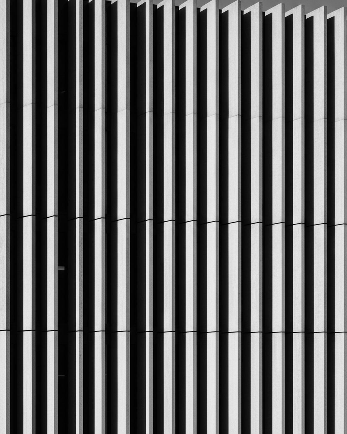 A facade of vertical board-formed concrete fins casting deep shadow — the active sheet